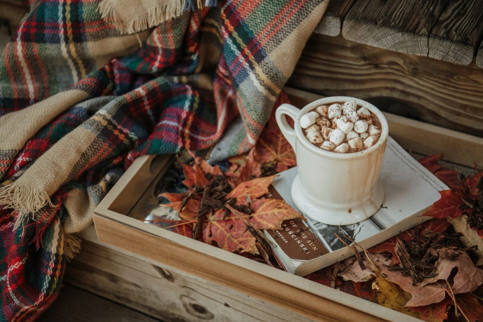 Un break ou on ralentit, couverture, chocolat chaud, feuilles déposées sur une table.